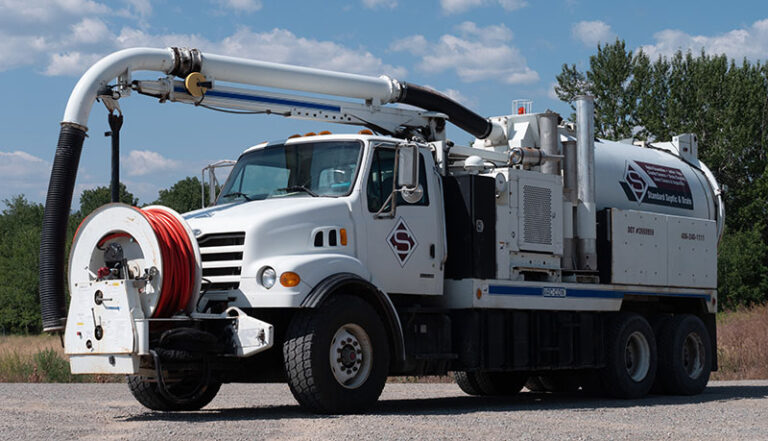 Large Standard Drain Cleaning truck with big hose spool mounted on the front and connected to a large tank on the back of the truck 